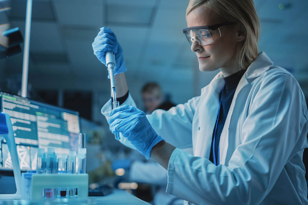 An image of a scientist or doctor filling a test tube.